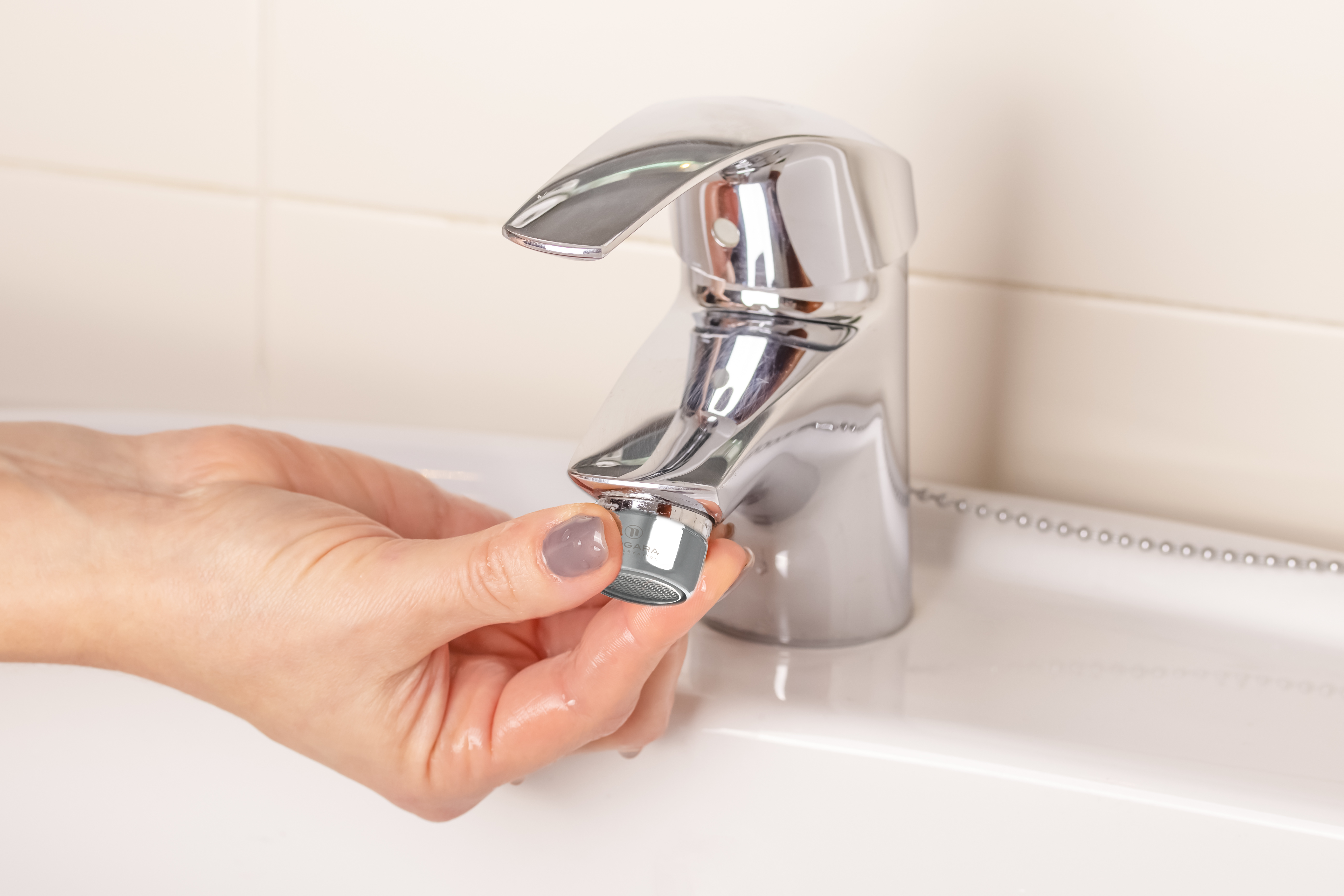 The-girls-hand-twists-off-twists-the-faucet-aerator-in-the-bathroom